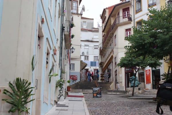Rua estreita do centro histórico de Coimbra, com balcões e um letreiro de fado